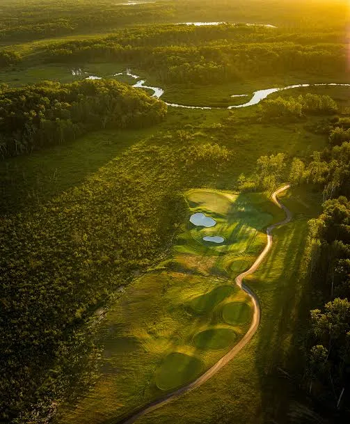 Golden-hour aerial of a north-woods golf hole